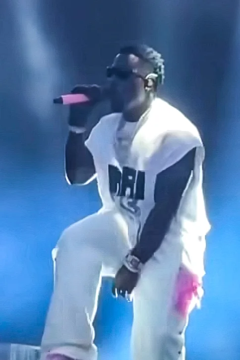 Frenna in een wit outfit op het podium met een mat roze gewrapte draadloze microfoon van WRPPN