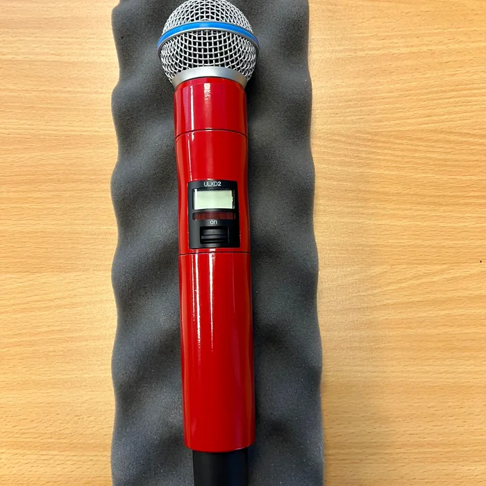 Draadloze Shure-microfoon gewrapt in rood hoogglans, op grijs schuim