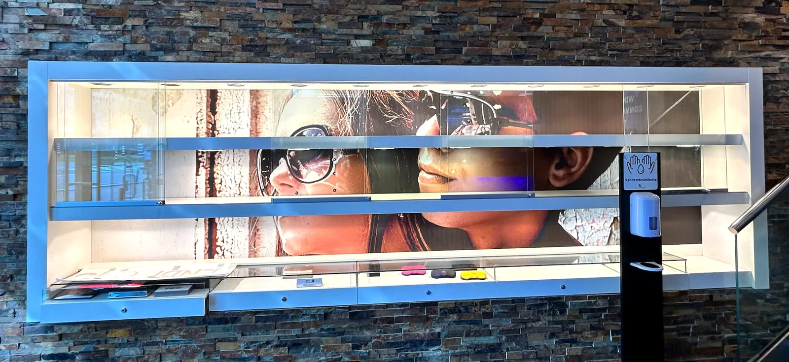 Voor: dezelfde vitrinewand met een drukke fotoprint