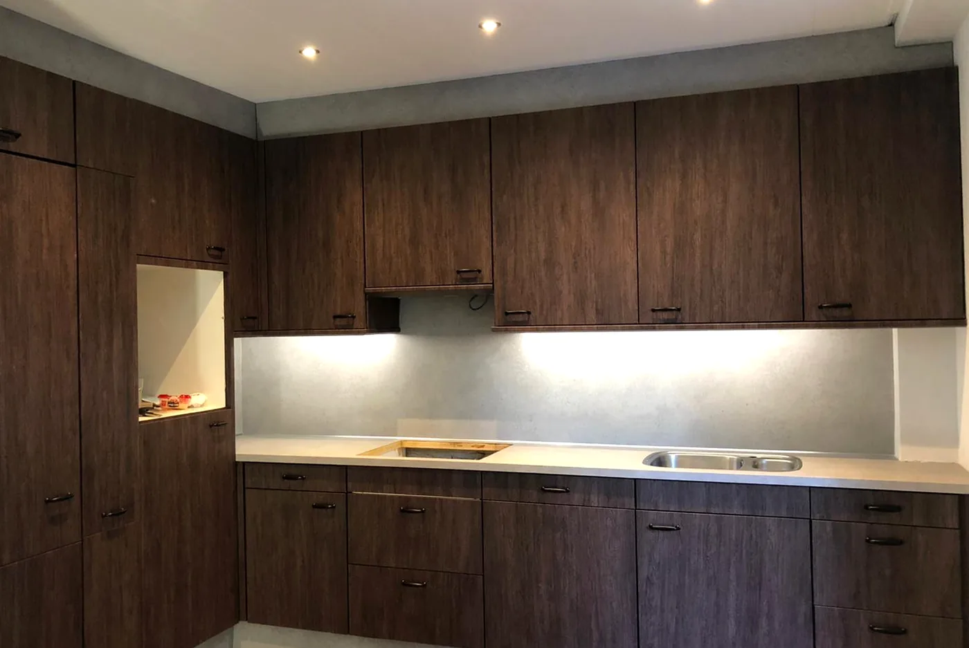 Na: keuken met donkere houtnerf fronten en een lichte betonlook werkblad en achterwand