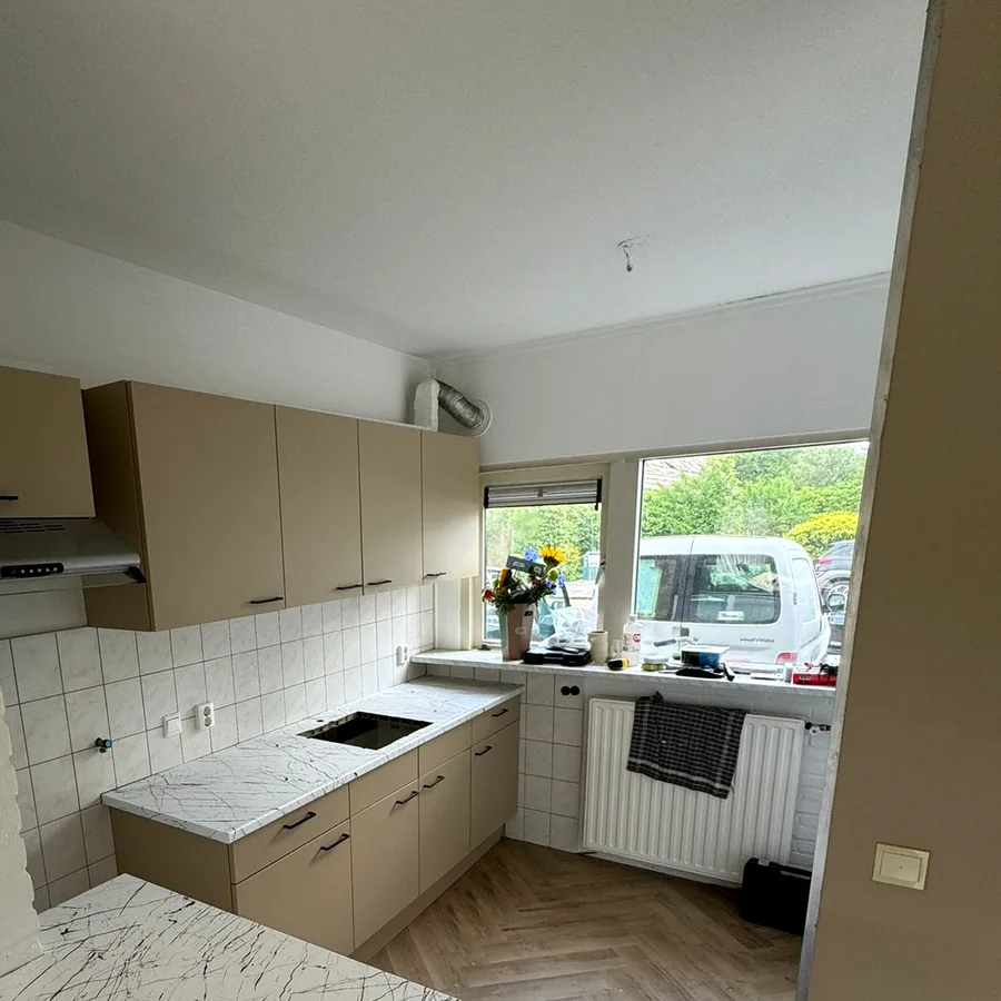 Overzicht van de taupe keuken met het schiereiland in witte marmerlook