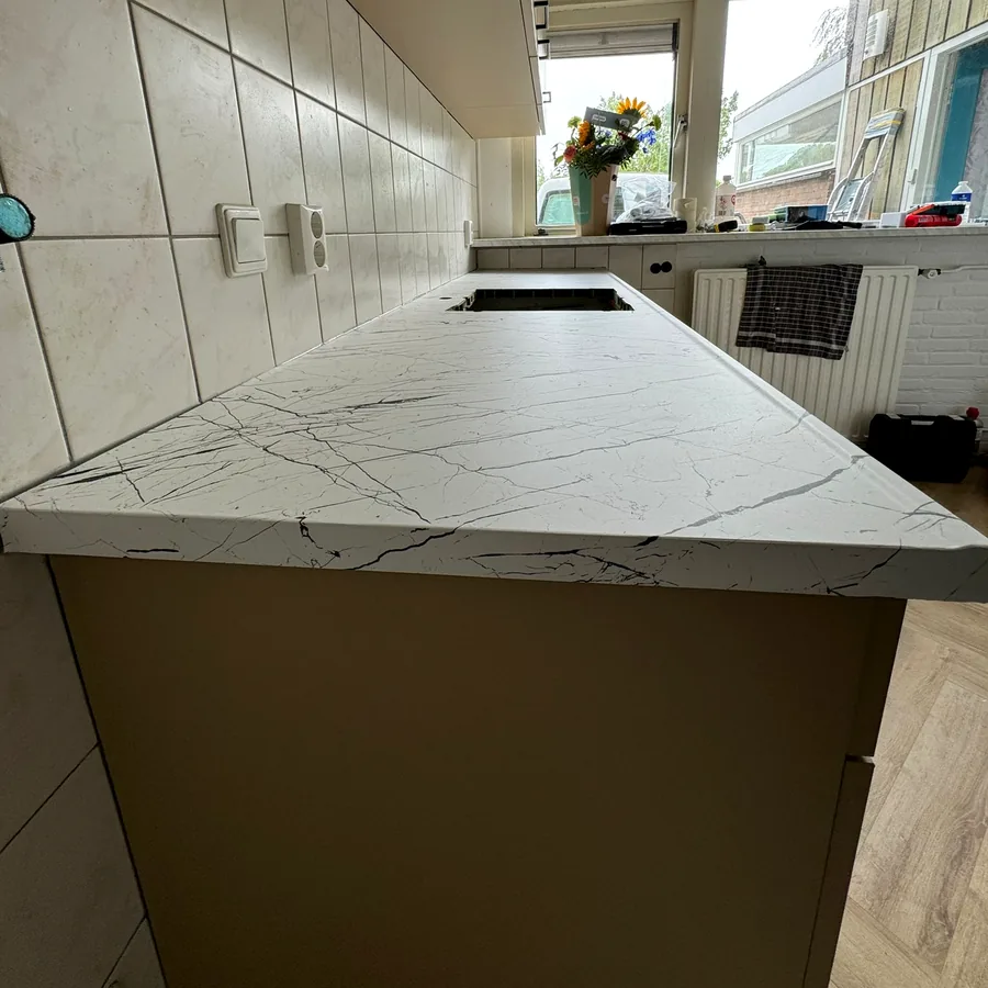 Werkblad in witte marmerlook van dichtbij, met taupe kastfronten