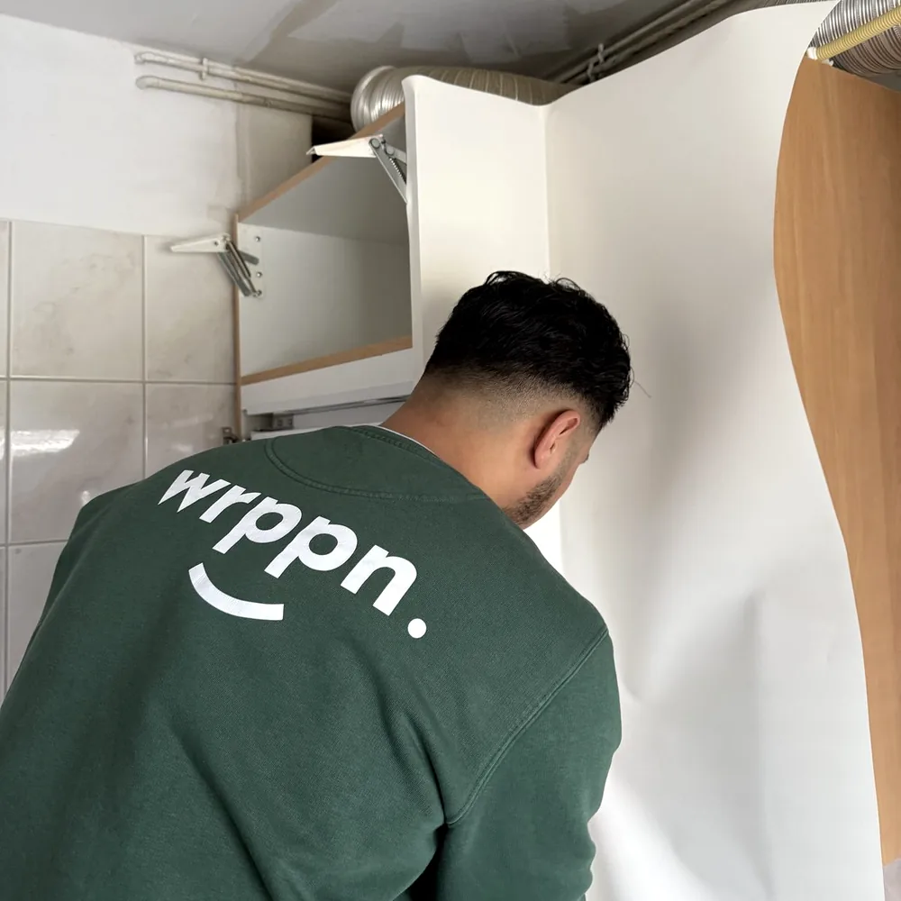 Monteur in een WRPPN-sweater brengt witte folie aan op een wand