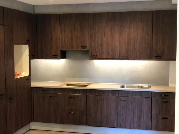 Na: keuken in donkere houtnerf met verlichting onder de kasten