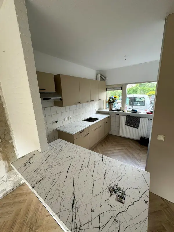 Overzicht van de taupe keuken met het schiereiland in witte marmerlook