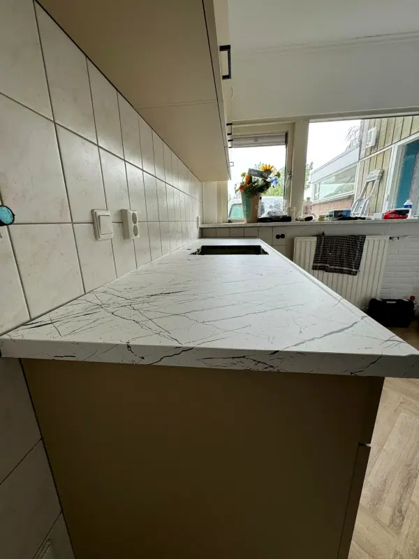 Werkblad in witte marmerlook van dichtbij, met taupe kastfronten