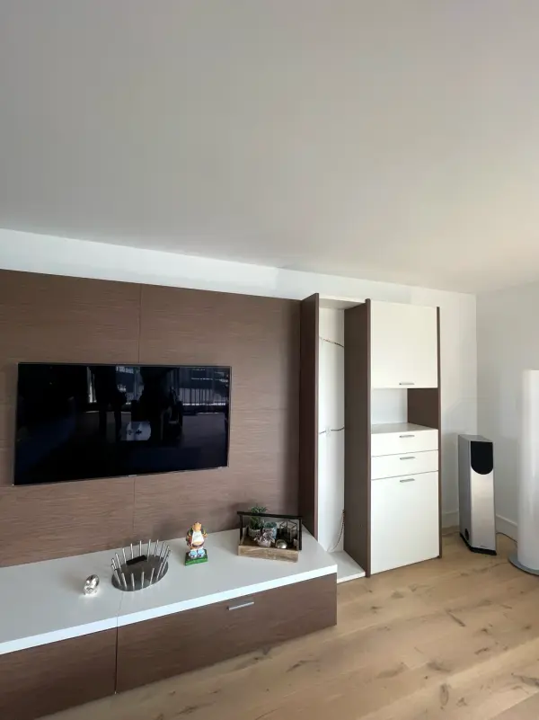 Tv-wand met hoge witte kast ernaast