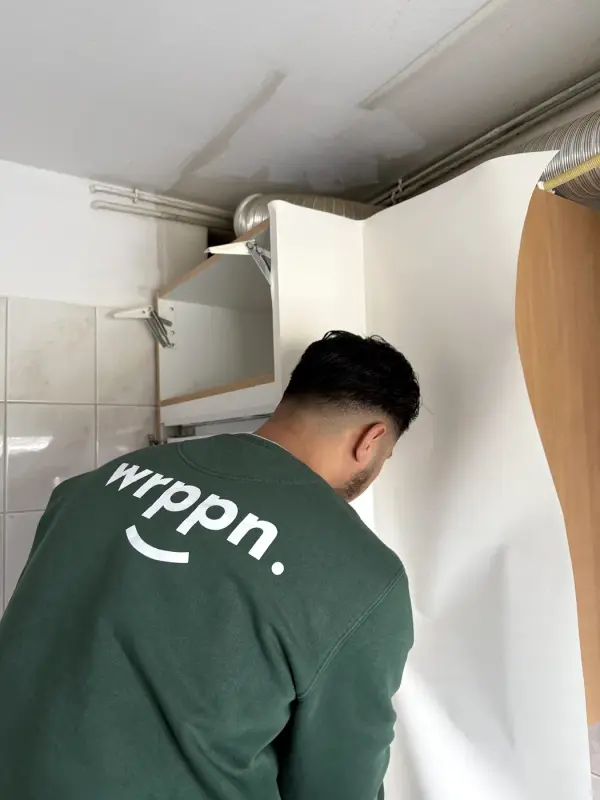 Monteur in een WRPPN-sweater brengt witte folie aan op een wand