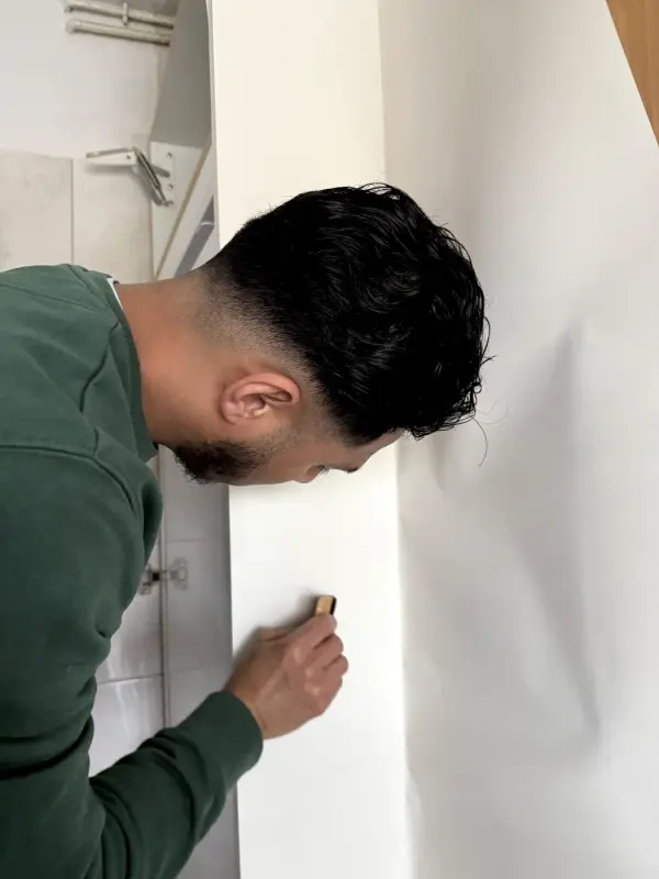 Monteur snijdt witte folie op maat met een mes