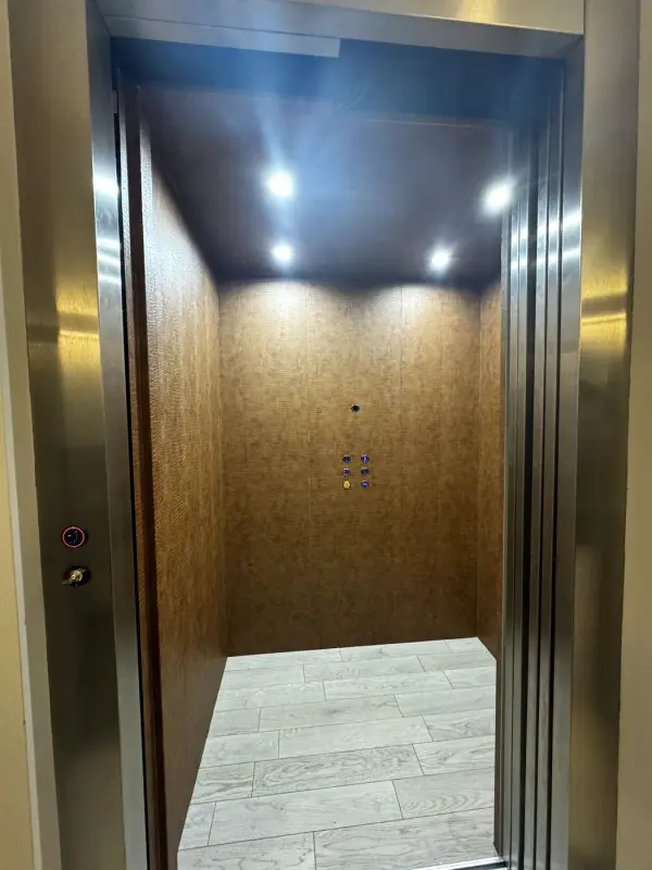 Liftcabine met open deuren en een achterwand in bruine leather look