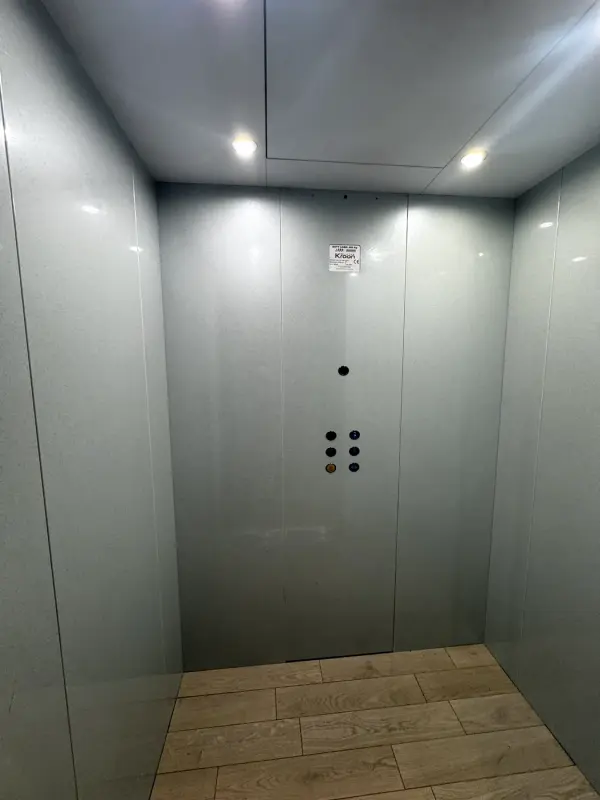 Voor: grijze achterwand van de liftcabine