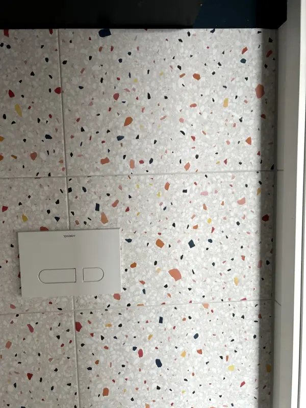 Na: toiletruimte in terrazzolook onder een zwarte plank