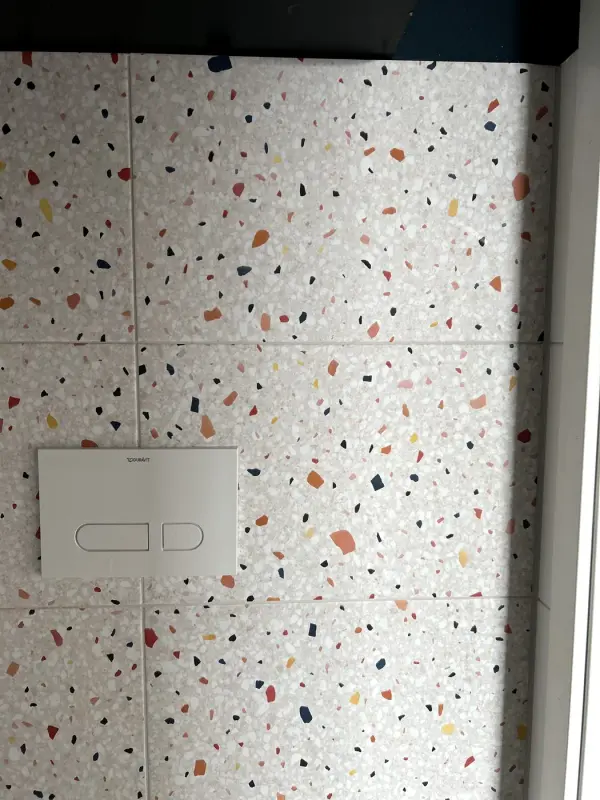 Na: tegelwand in terrazzolook met witte bedieningsplaat