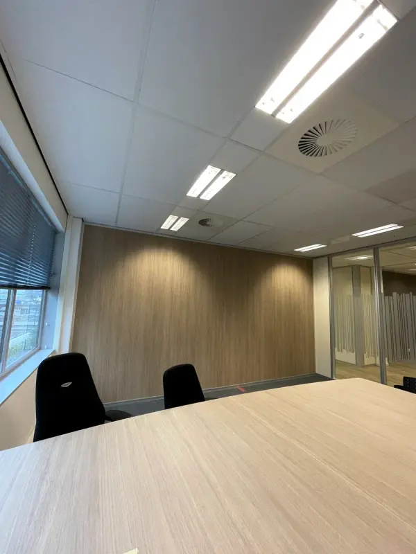 Vergaderruimte met een wand in lichte houtlook achter de tafel